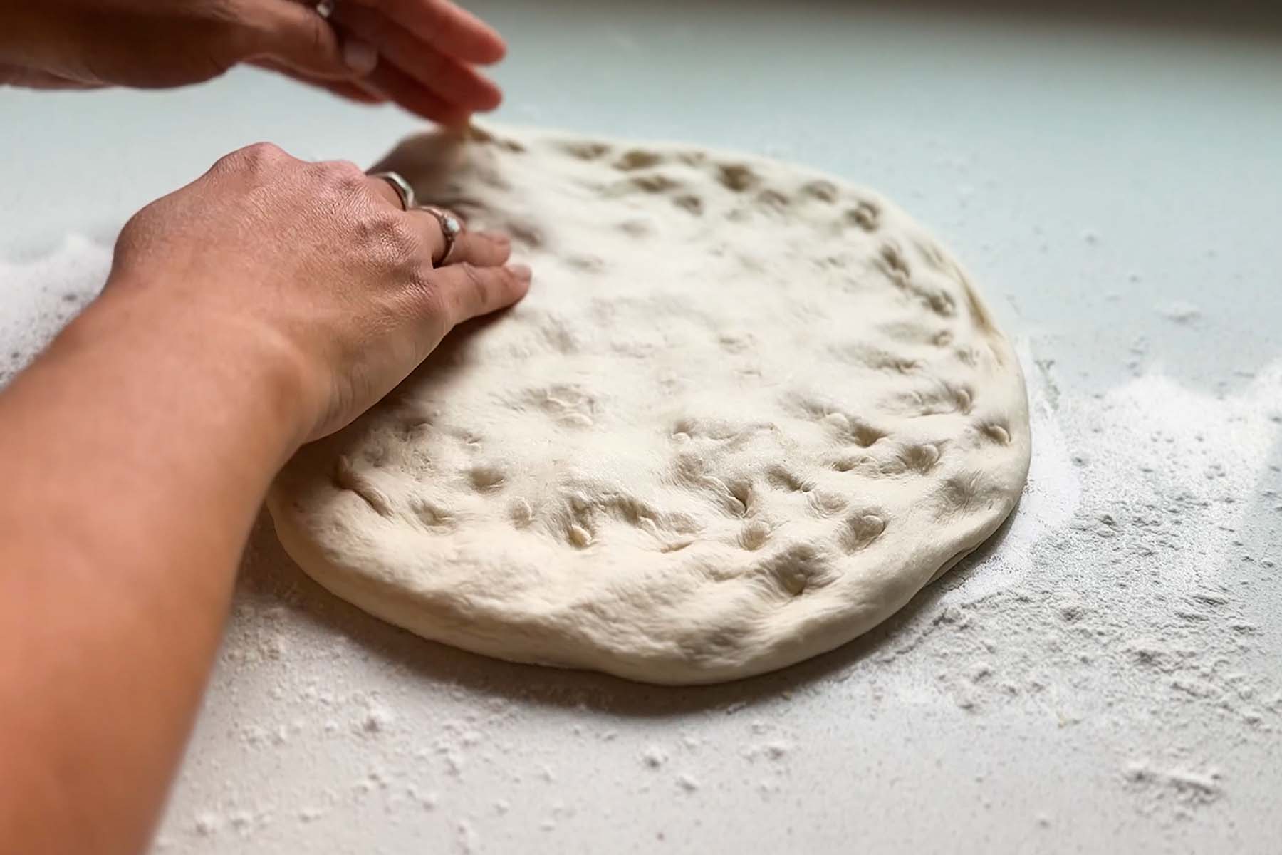 Pizza dough is shaped by hand.