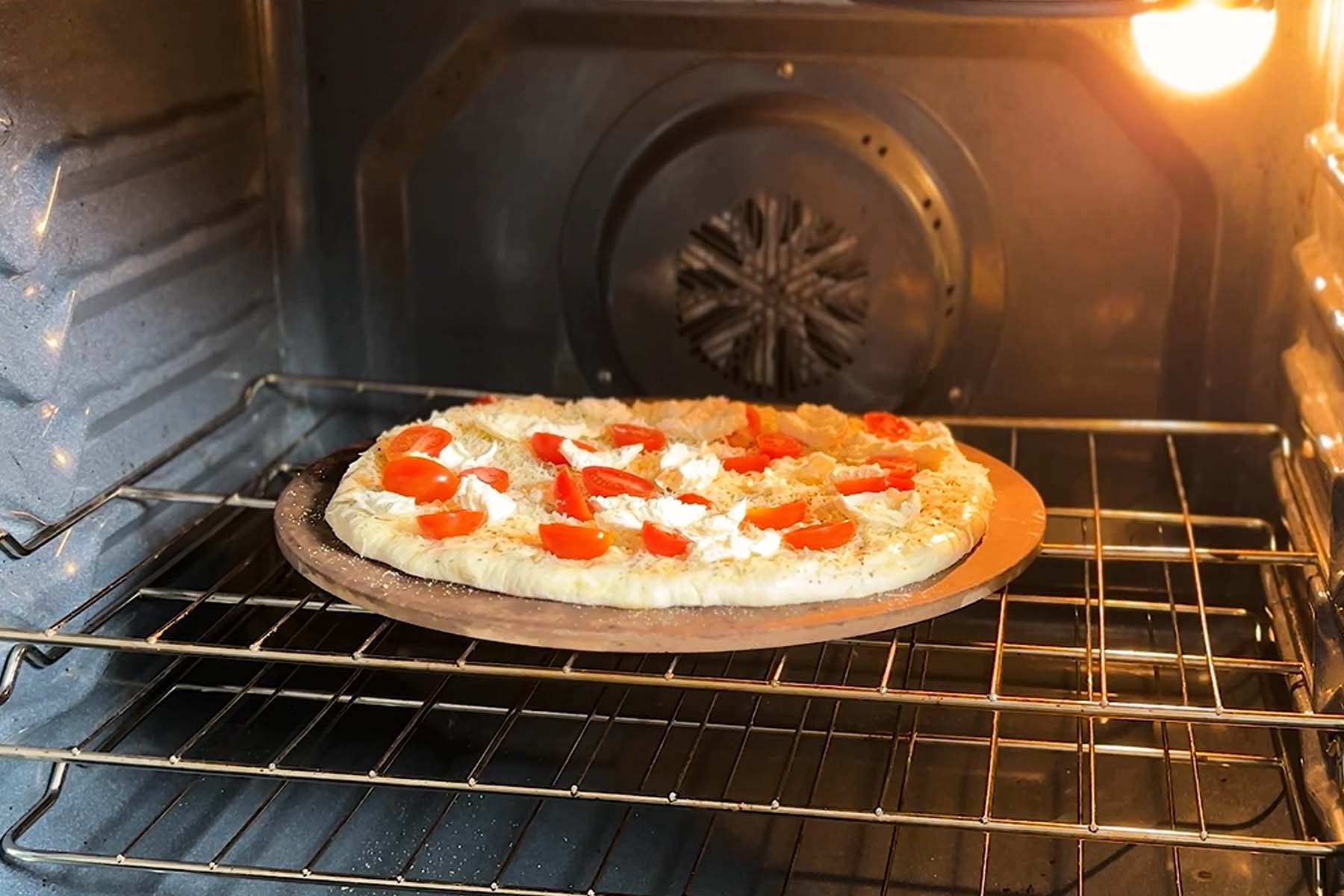 Pizza on a pizza stone in an oven.