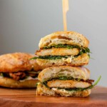 A stacked halved sandwich on a bun with chicken and spinach inside.