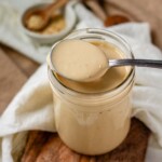 Creamy dressing in a jar with a spoon.