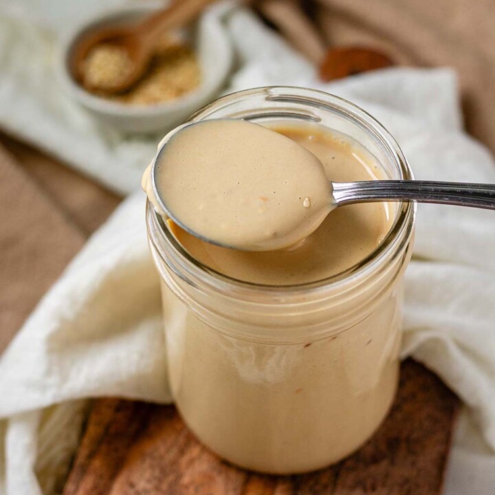 Creamy dressing in a jar with a spoon.