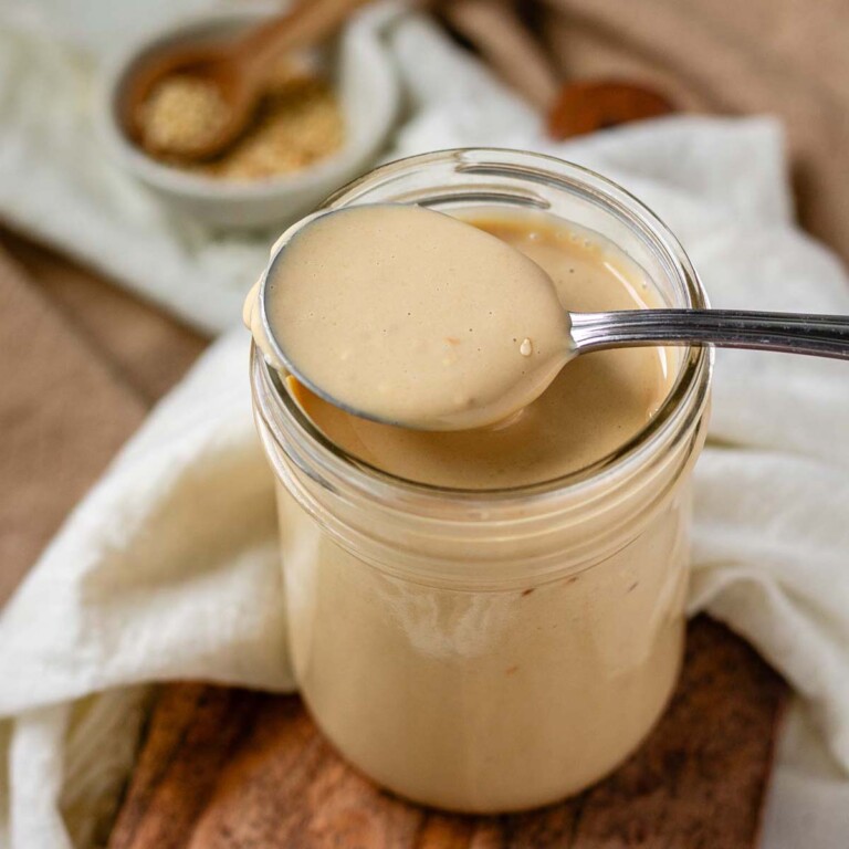 Creamy dressing in a jar with a spoon.