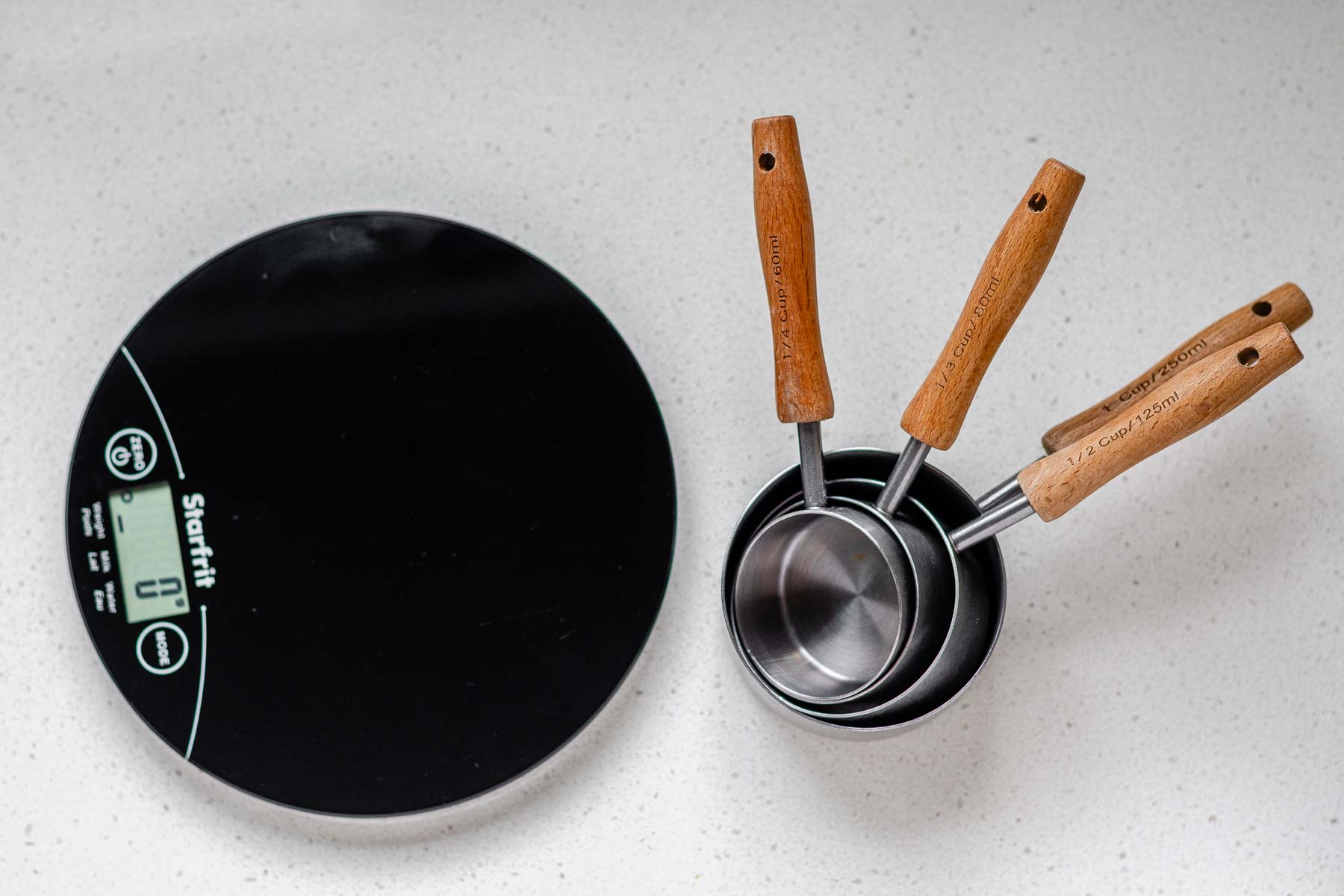 A kitchen scale beside measuring cups.