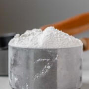 A measuring cup with flour in it with the text how to measure flour.