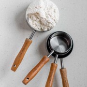 A measuring cup with flour in it with the text how to measure flour.
