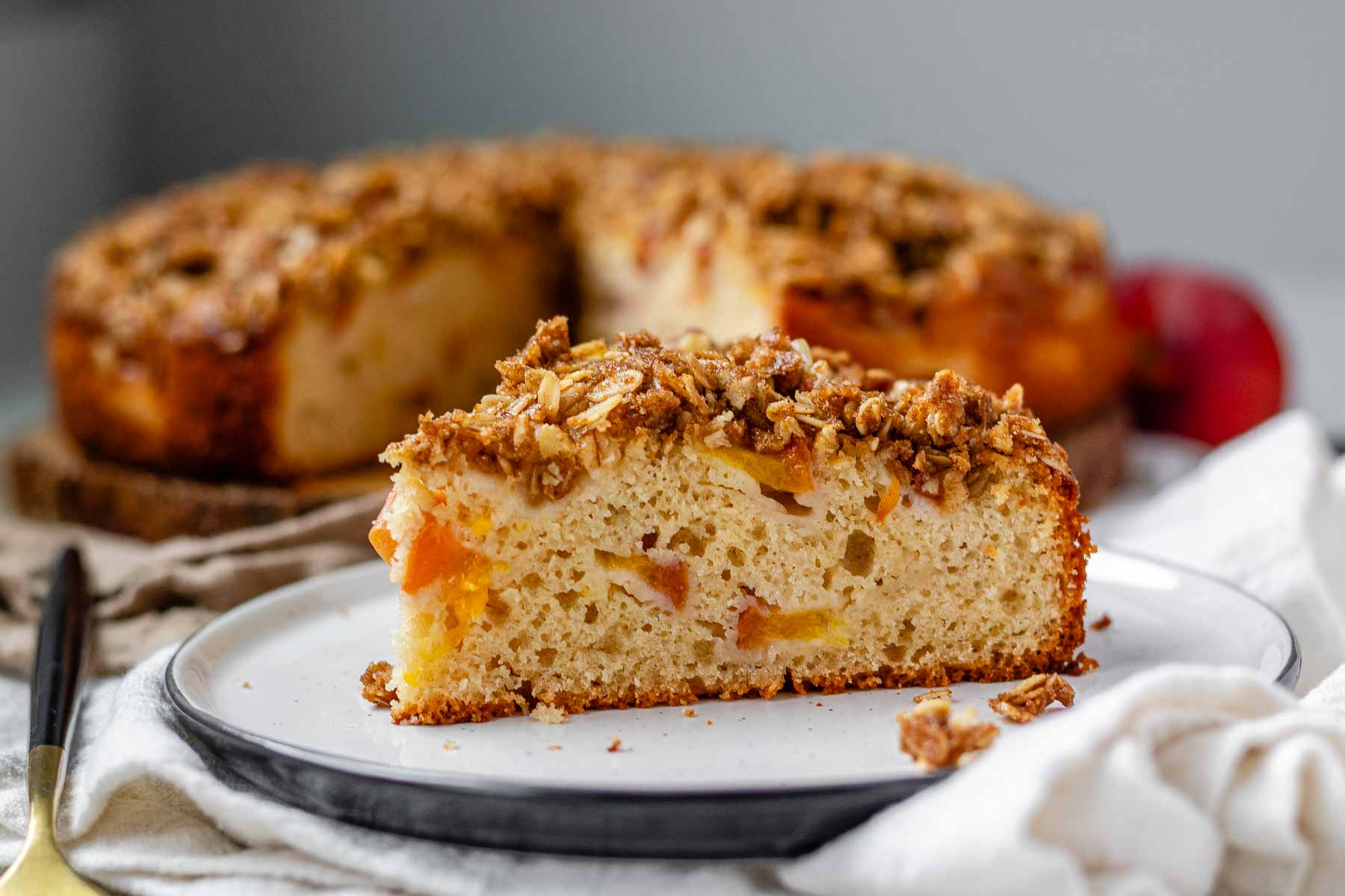 Cake with peaches inside and crumbled oats on top.