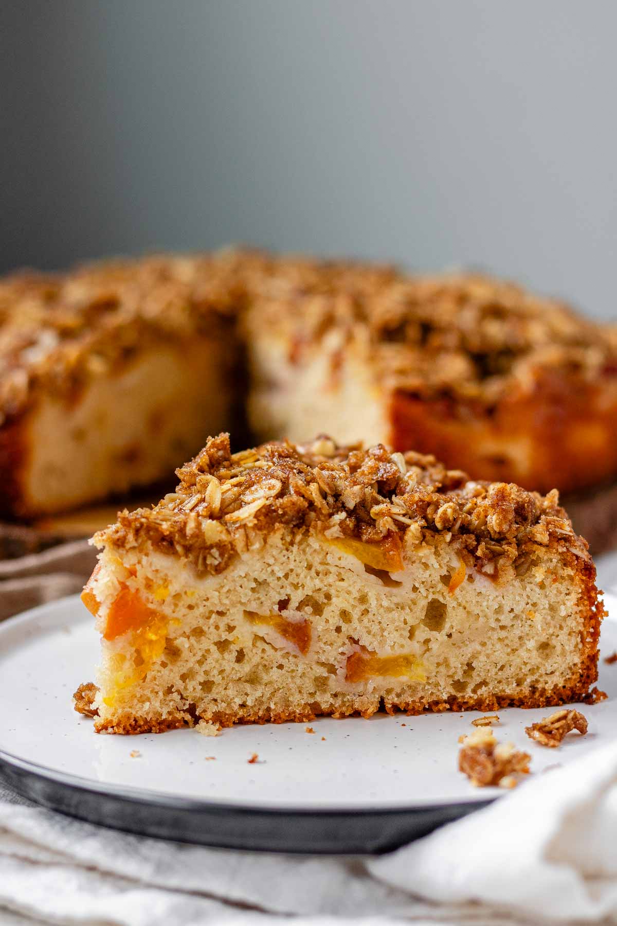 Cake with peaches inside and crumbled oats on top.