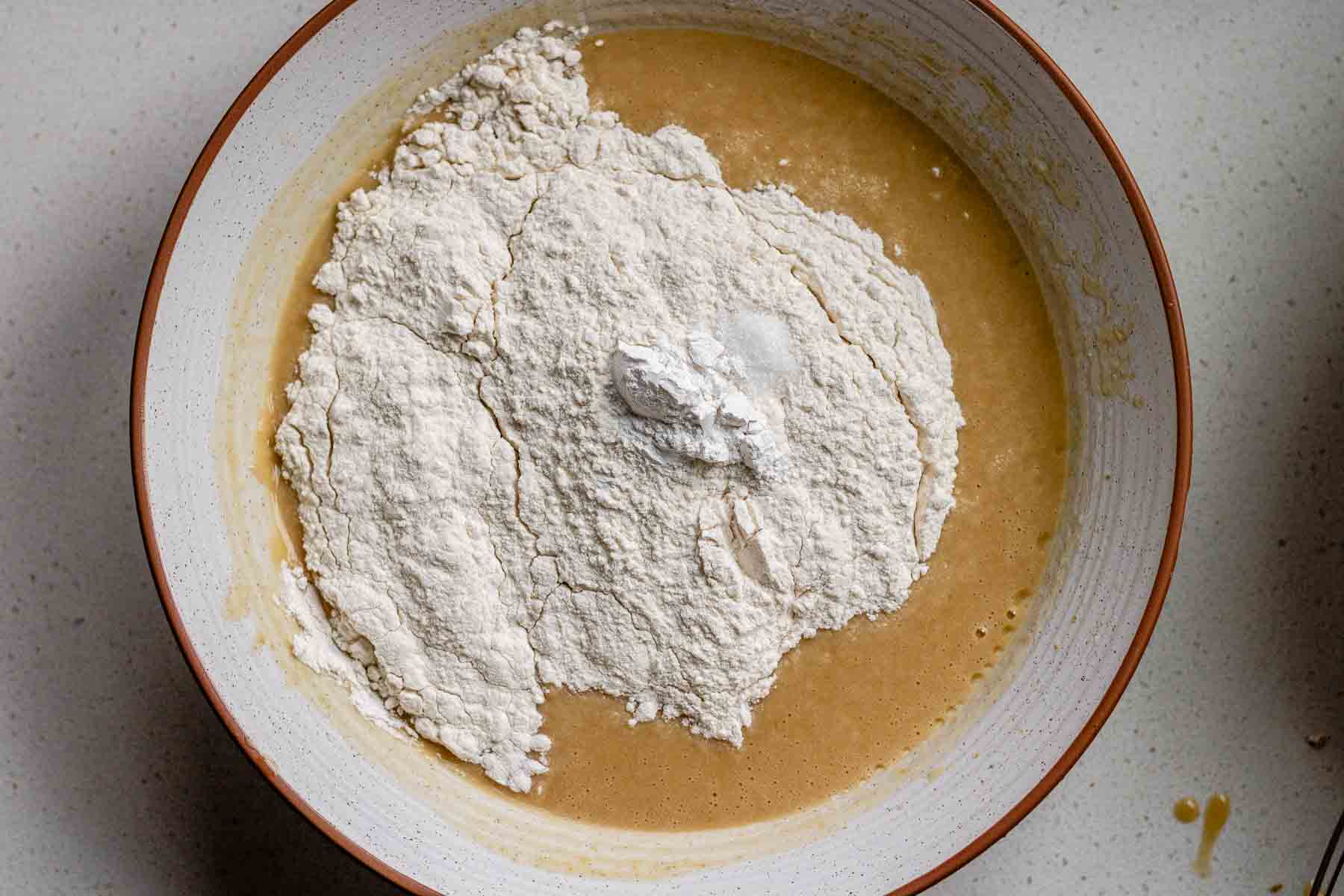 A bowl with cake batter, with flour on top.