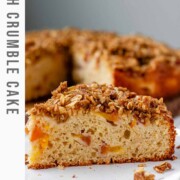Cake with peaches inside and crumbled oats on top with the text peach crumble cake.