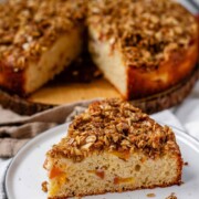 Cake with peaches inside and crumbled oats on top with the text fresh peach crumble cake.