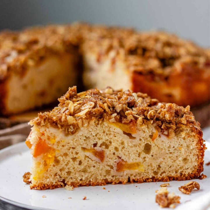 Cake with peaches inside and crumbled oats on top.