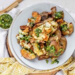 Cooked potatoes on a plate with green sauce.