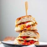 A stacked halved sandwich on a bun with halloumi and tomatoes inside.
