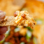 Spoonful of cheesy buffalo chickpea dip being scooped from the baking dish.