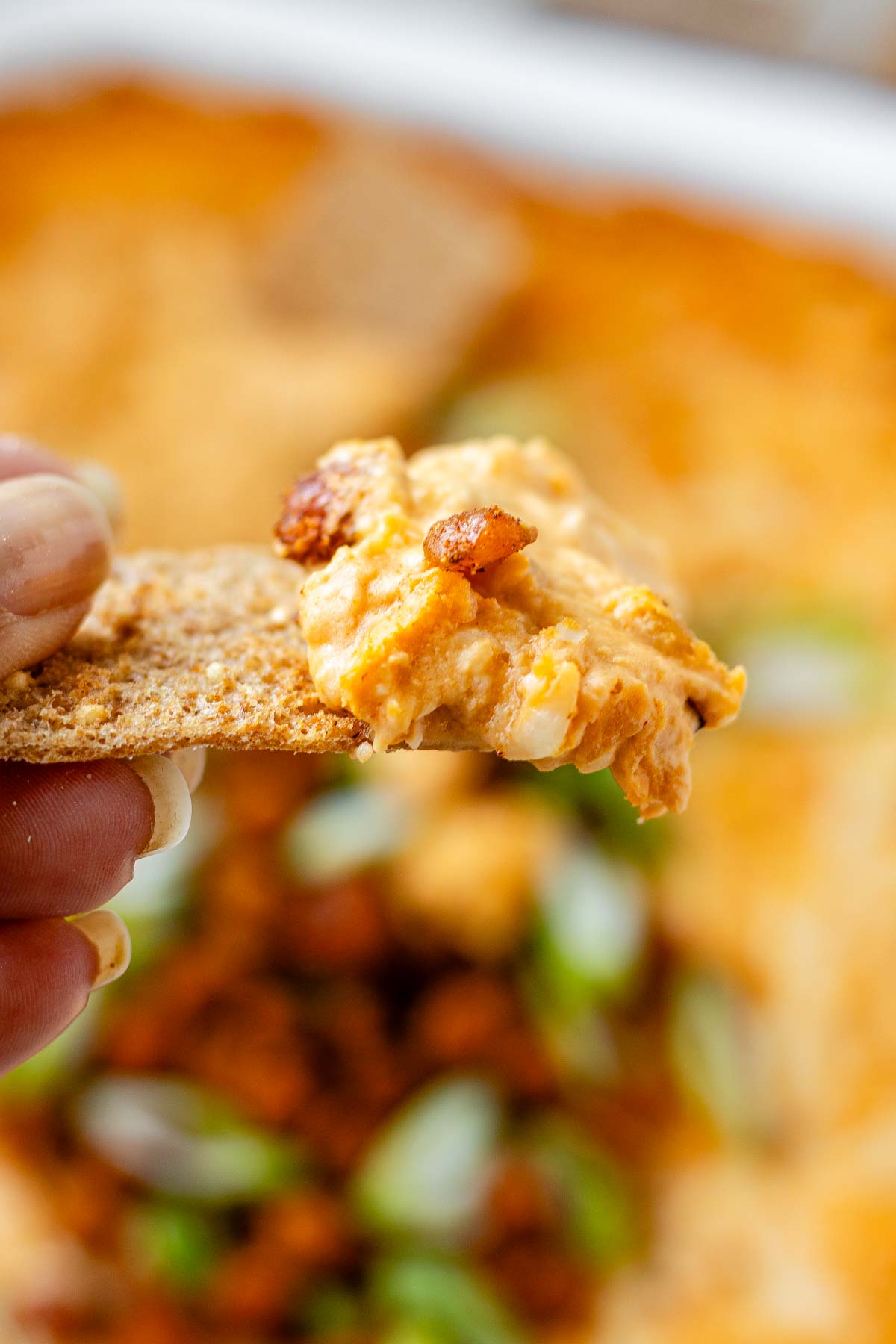 Spoonful of cheesy buffalo chickpea dip being scooped from the baking dish.