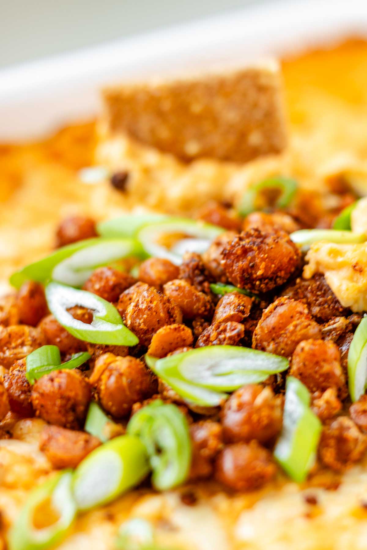 Golden baked buffalo chickpea dip fresh from the oven with melted cheese and pan-fried crispy chickpeas on top.