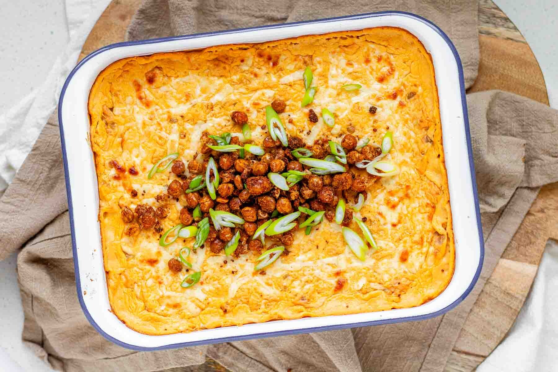 Golden baked buffalo chickpea dip fresh from the oven with melted cheese and pan-fried crispy chickpeas on top.