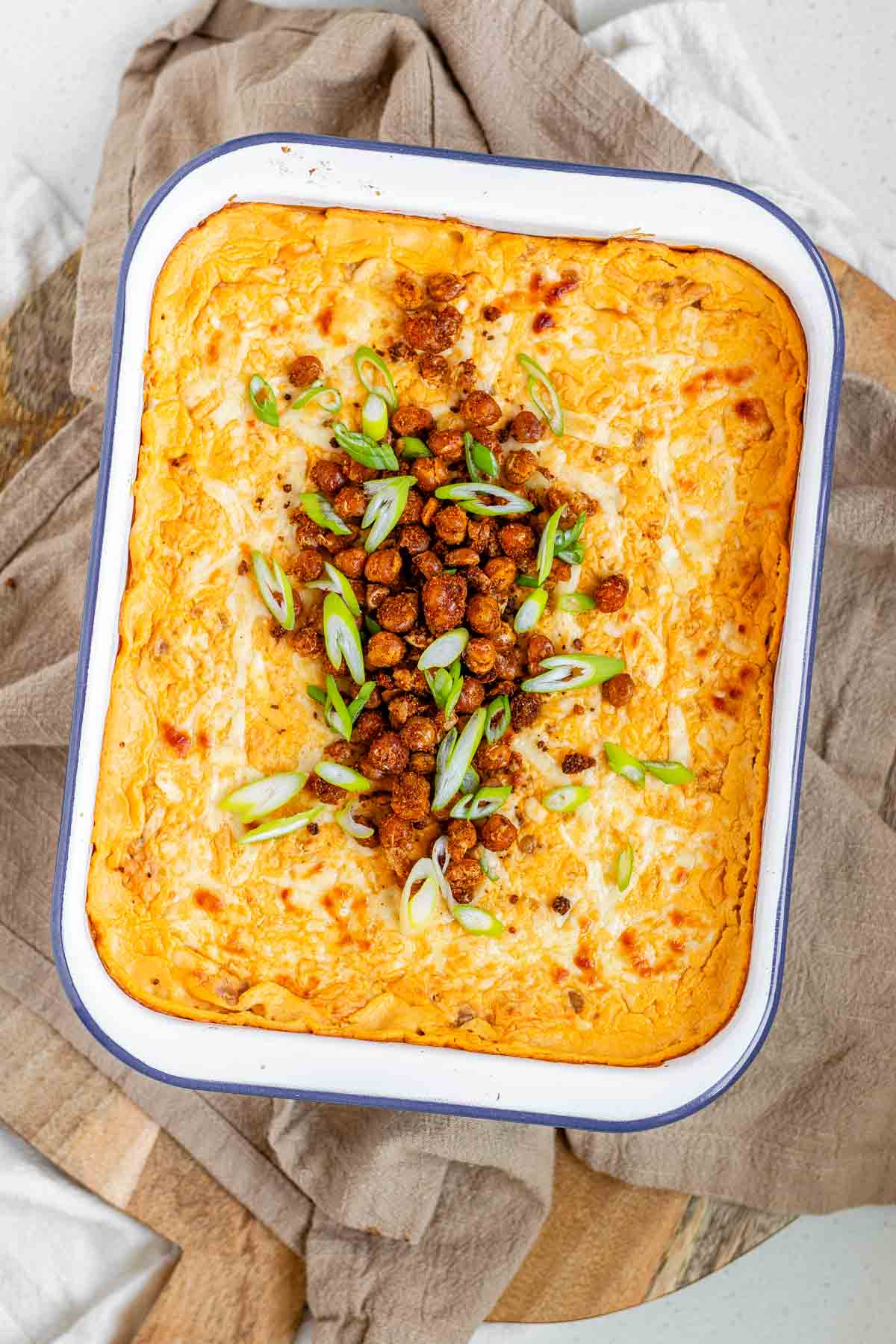 Golden baked buffalo chickpea dip fresh from the oven with melted cheese and pan-fried crispy chickpeas on top.