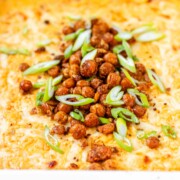 Golden baked buffalo chickpea dip fresh from the oven with melted cheese and pan-fried crispy chickpeas on top.