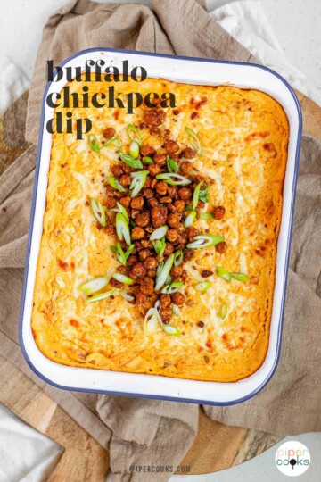 Golden baked buffalo chickpea dip fresh from the oven with melted cheese and pan-fried crispy chickpeas on top with the text buffalo chickpea dip.