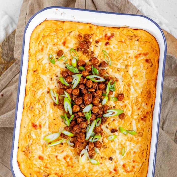 Golden baked buffalo chickpea dip fresh from the oven with melted cheese and pan-fried crispy chickpeas on top.