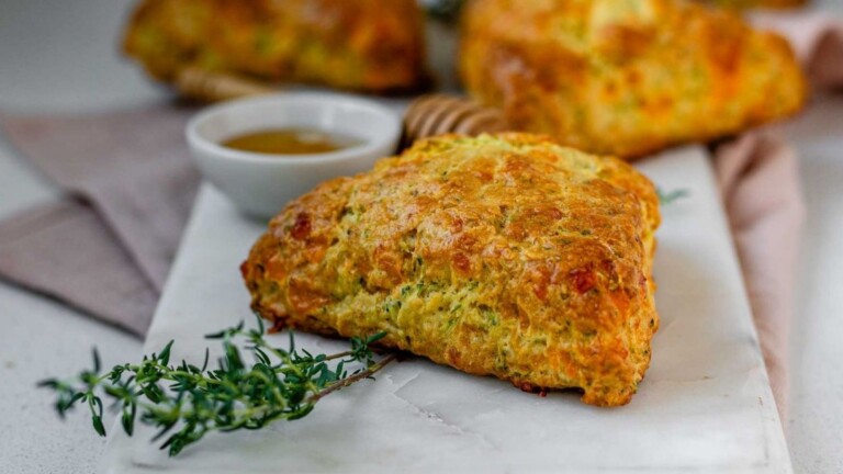 A scone on a board beside a sprig of thyme.