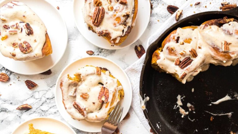 Plates of cinnamon rolls topped with icing and pecans.