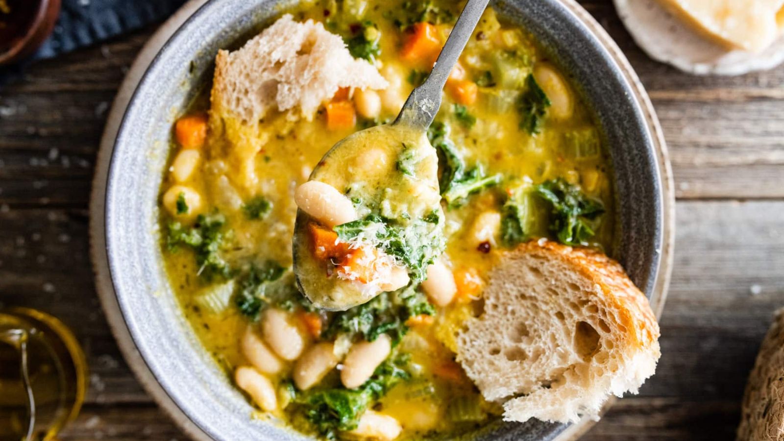 A bowl of soup with torn bread chunks in it.