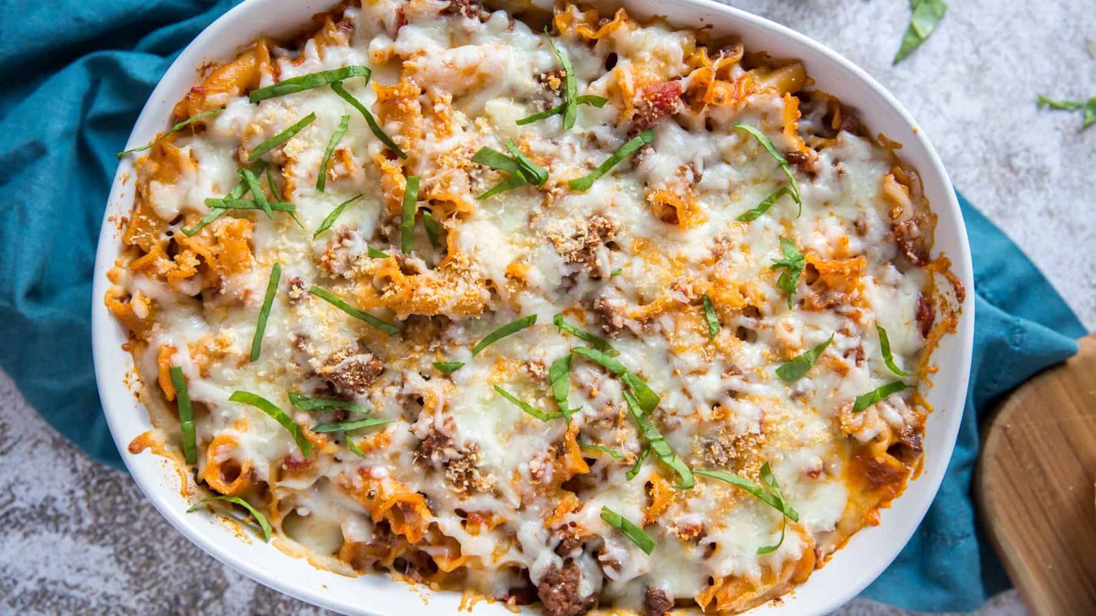 A casserole topped with melted cheese and chopped herbs.