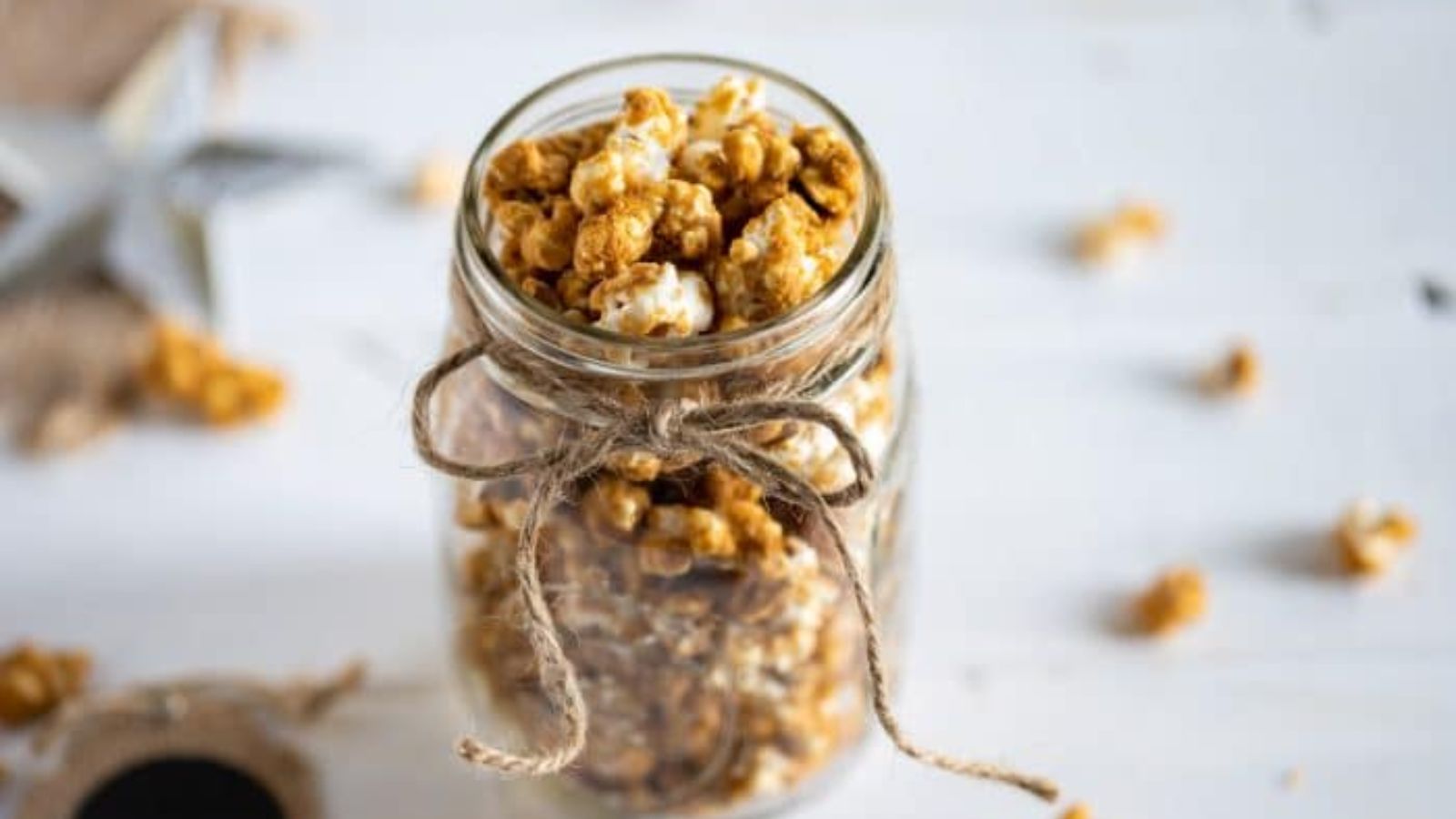 Gingerbread caramel corn in a glass jar with twine tied around the rim.