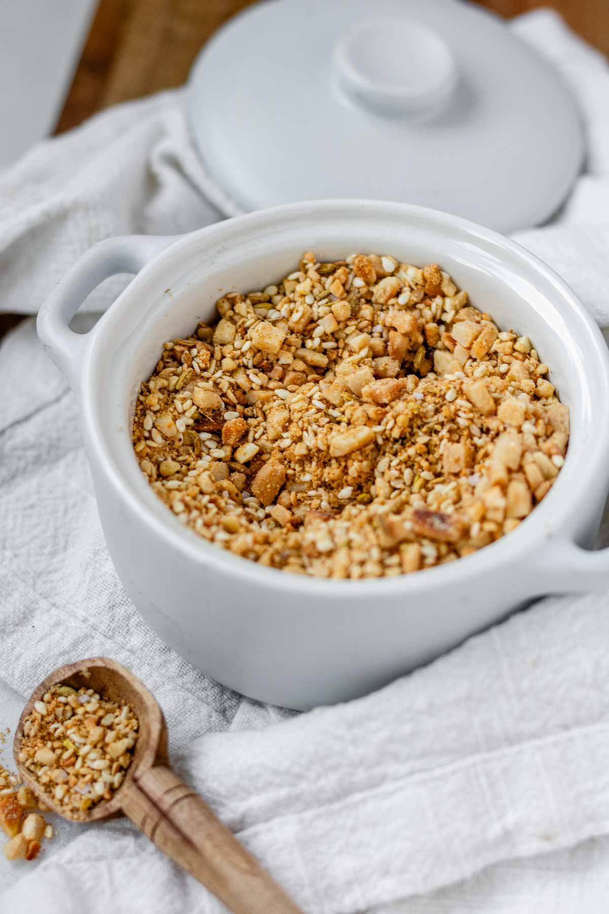 Close-up of homemade almond dukkah in a small bowl, showing toasted almonds, sesame seeds, and spices.