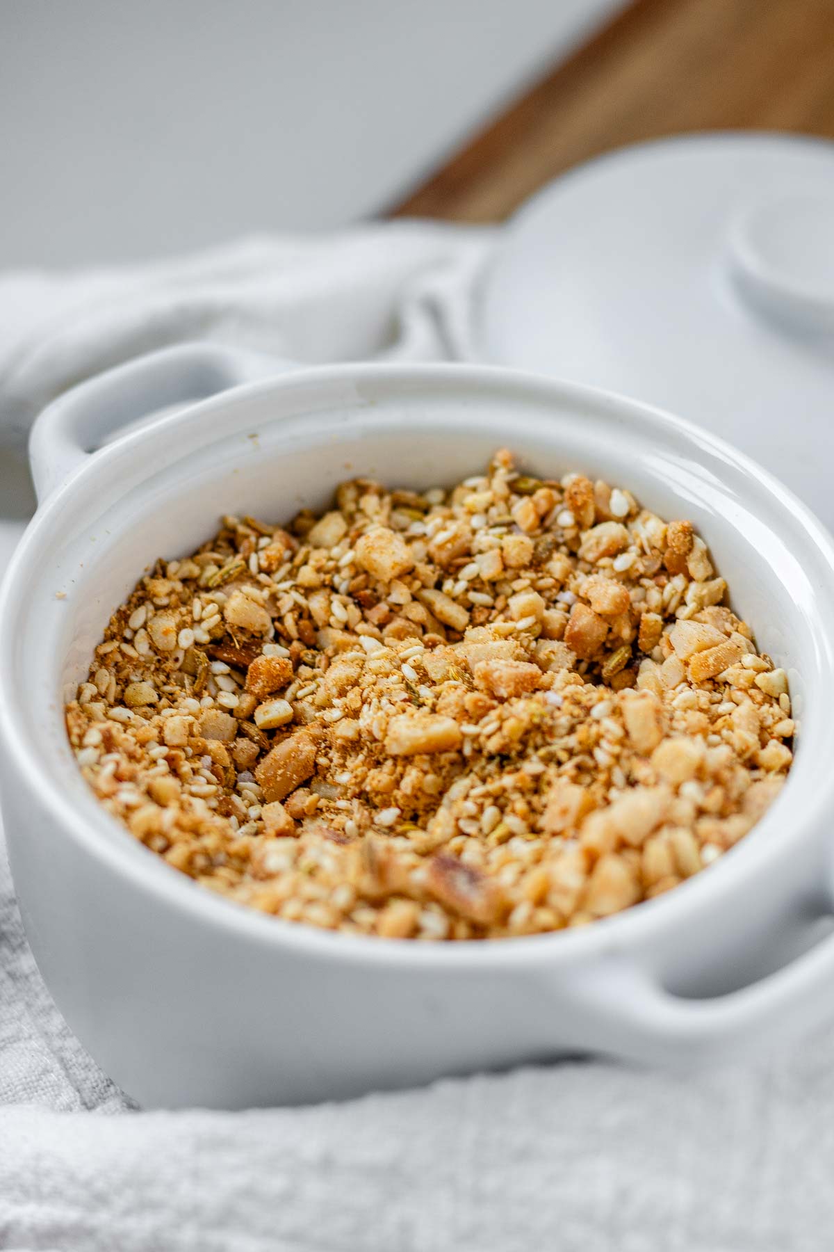 Close-up of homemade almond dukkah in a small bowl, showing toasted almonds, sesame seeds, and spices.