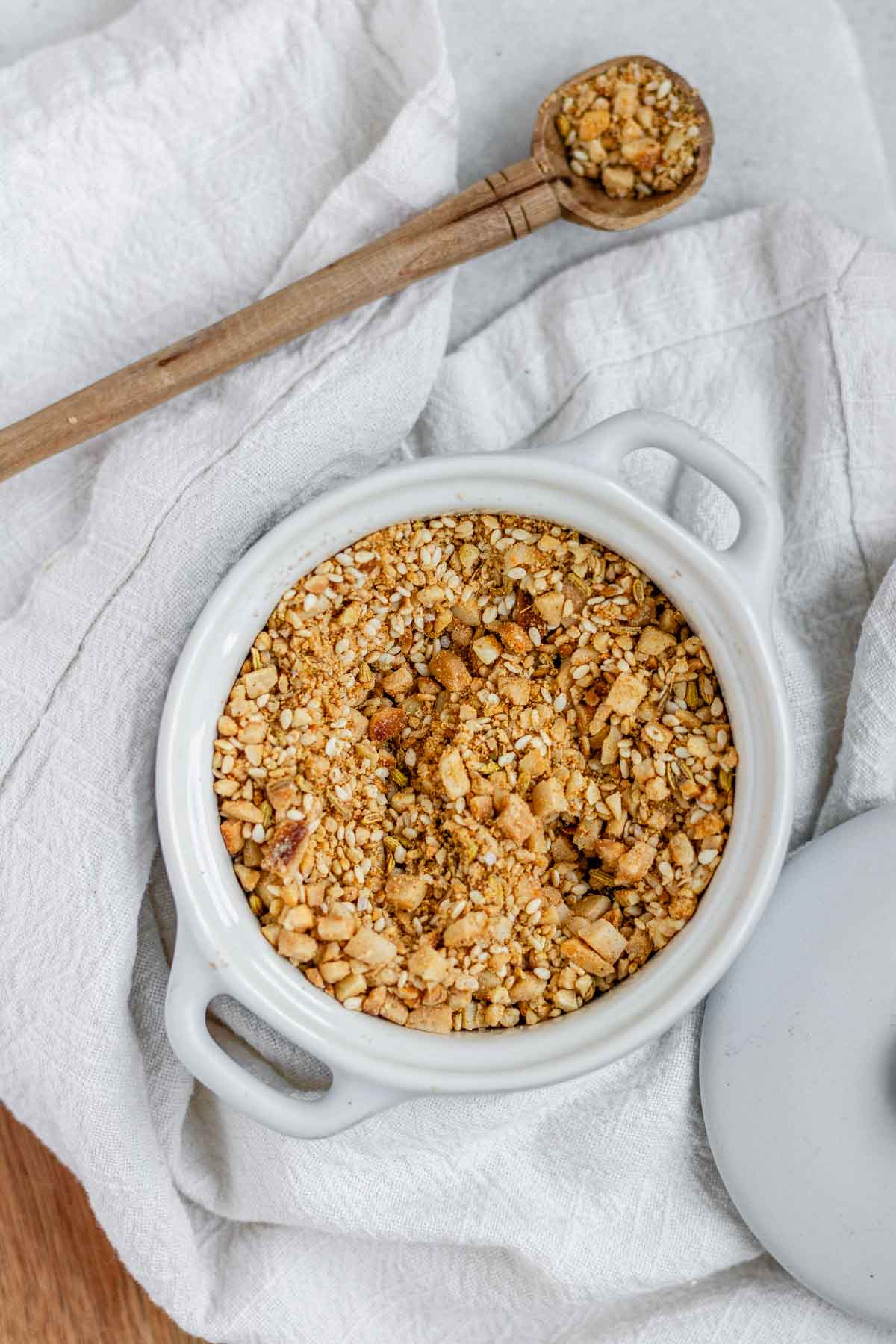 Close-up of homemade almond dukkah in a small bowl, showing toasted almonds, sesame seeds, and spices.