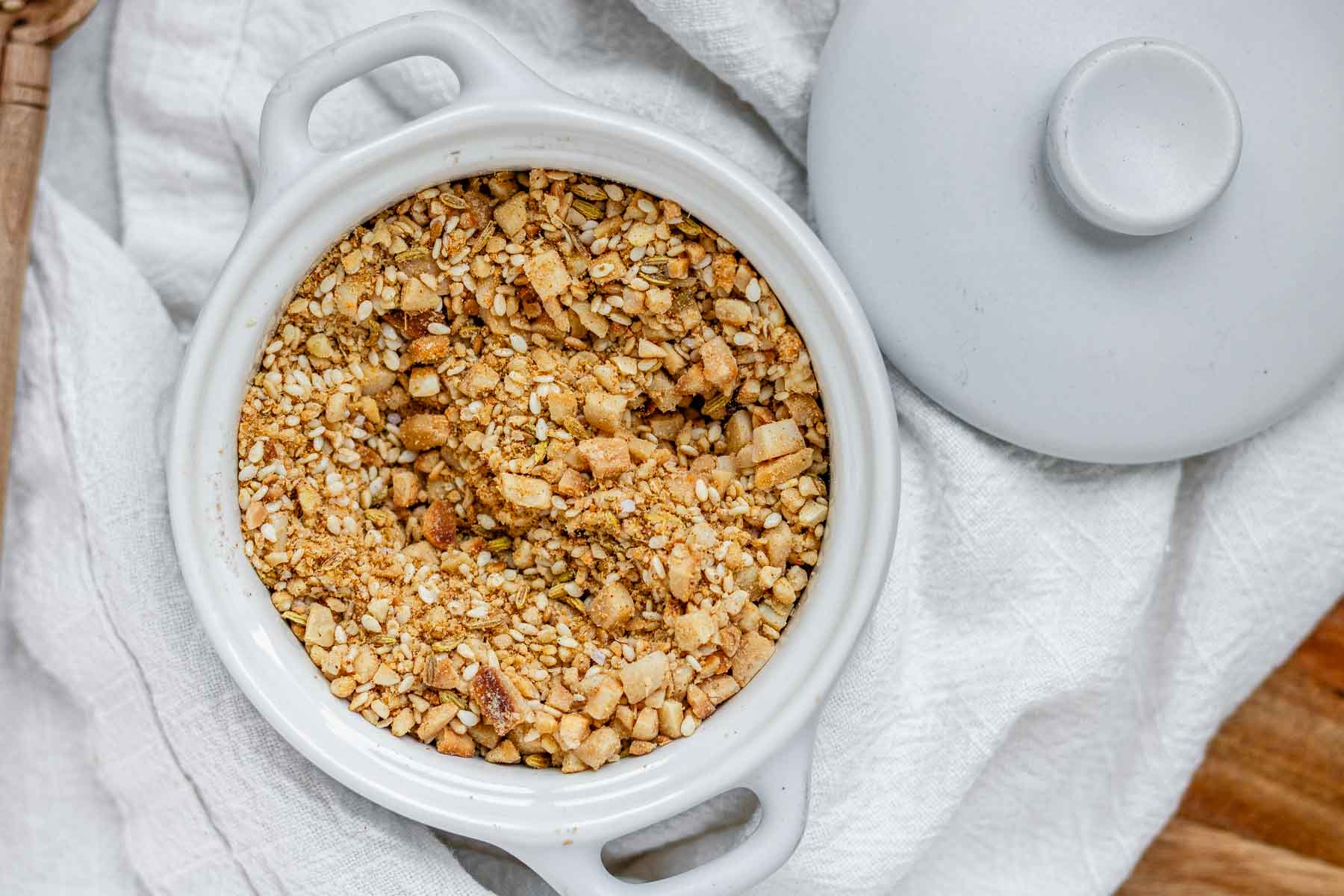 Close-up of homemade almond dukkah in a small bowl, showing toasted almonds, sesame seeds, and spices.