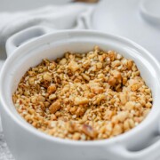 Close-up of homemade almond dukkah in a small bowl, showing toasted almonds, sesame seeds, and spices with the text almond dukkah.