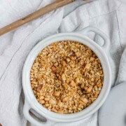 Close-up of homemade almond dukkah in a small bowl, showing toasted almonds, sesame seeds, and spices with the text almond dukkah.
