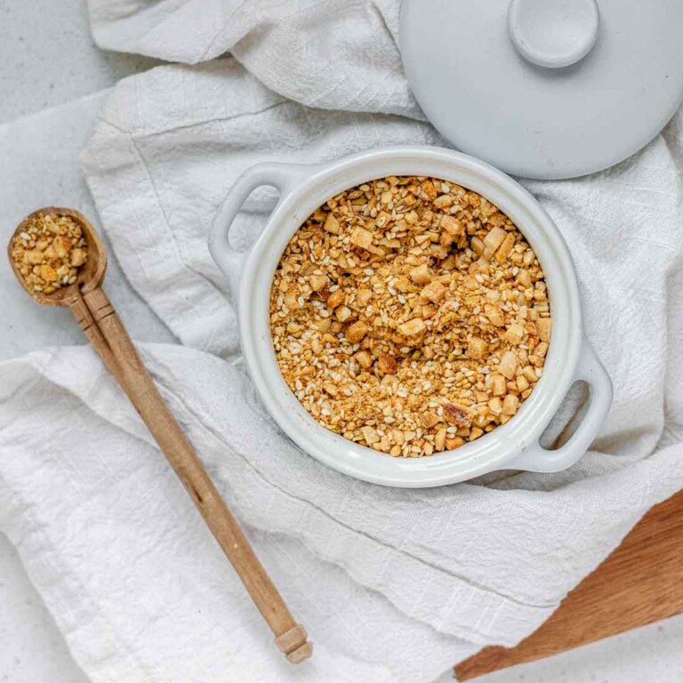 Close-up of homemade almond dukkah in a small bowl, showing toasted almonds, sesame seeds, and spices.