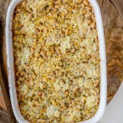 Baked rice and artichoke casserole topped with melted Havarti and Parmesan cheese in a white dish and a plate with the text artichoke bake.