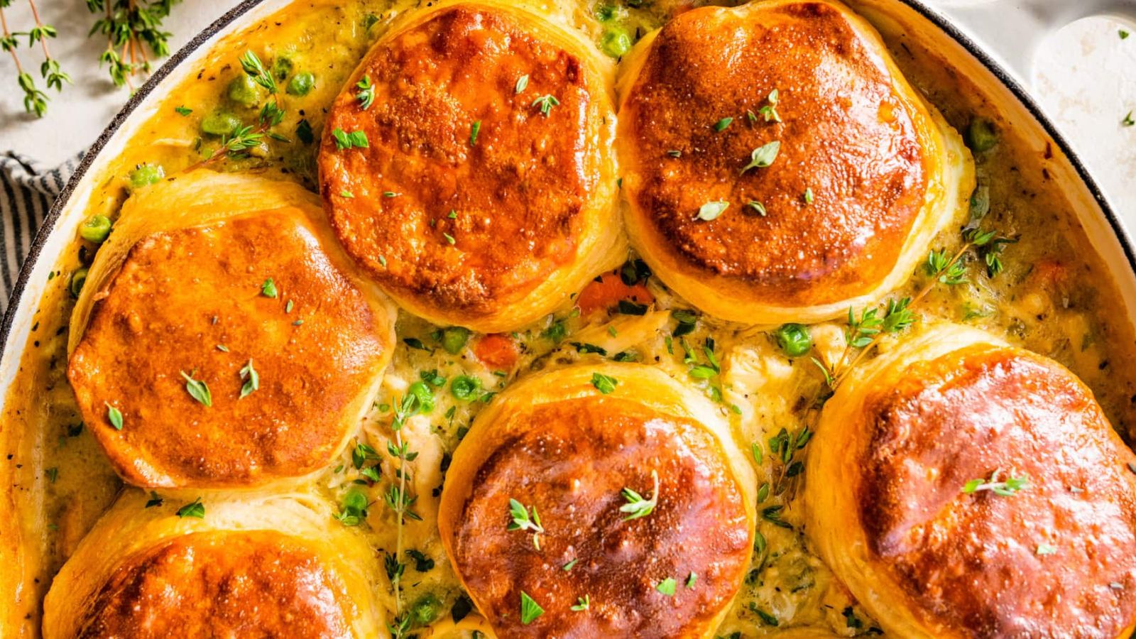 Sauce in a pan topped with golden biscuits.