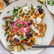 Crispy homemade Dukkah Fries served with tahini yogurt sauce, feta, olives, and pickled red onions.