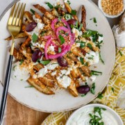 Crispy homemade Dukkah Fries served with tahini yogurt sauce, feta, olives, and pickled red onions.