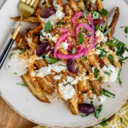 Crispy homemade Dukkah Fries served with tahini yogurt sauce, feta, olives, and pickled red onions.