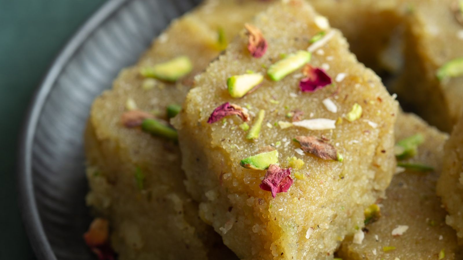 A close up of a piece of pistachio halwa with crushed pistachio on top.