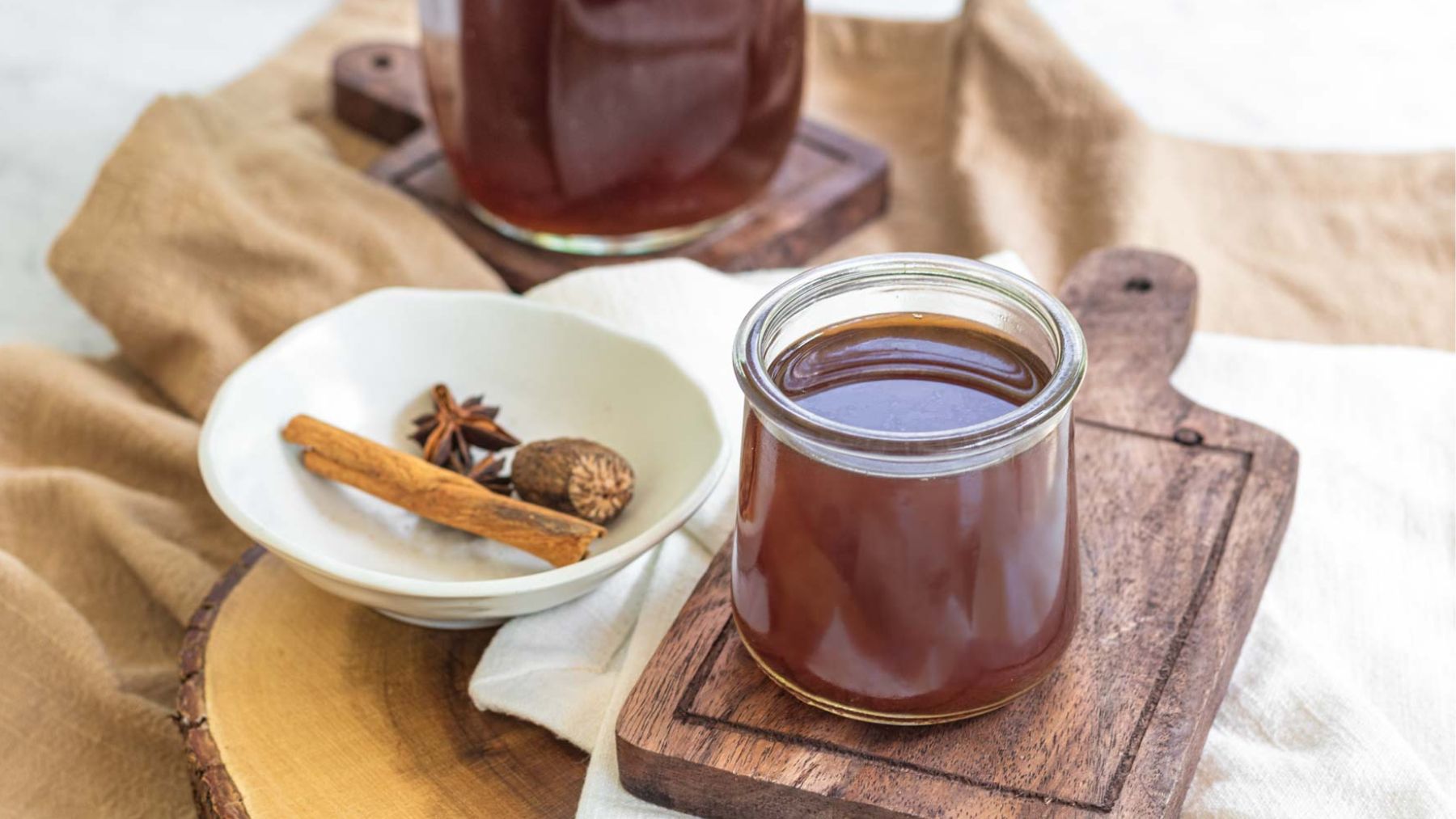 Chai concentrate in a glass jar next to a bowl of whole spices.
