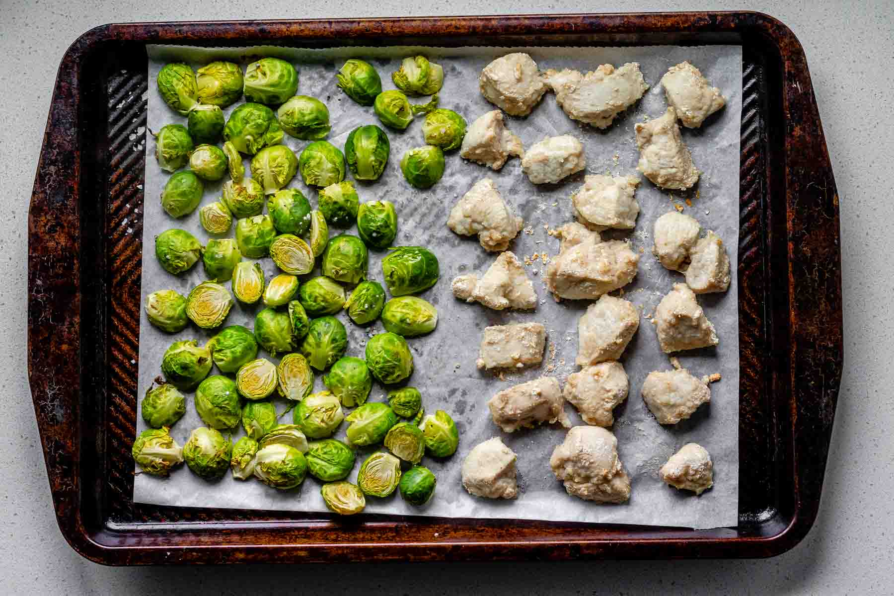 Sheet pan with spicy sesame chicken and roasted Brussels sprouts.