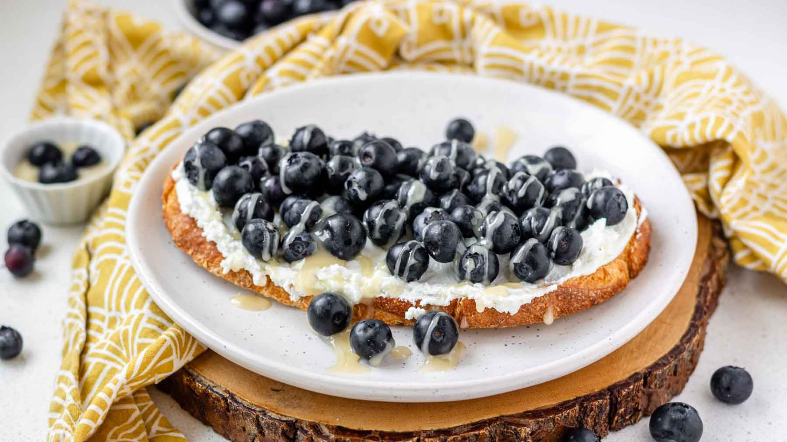 Goat cheese, blueberries, and drizzled honey on a slice of toast.