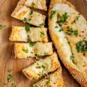 Boat-shaped baked dough filled with melted cheese sliced with the text cheese pide.