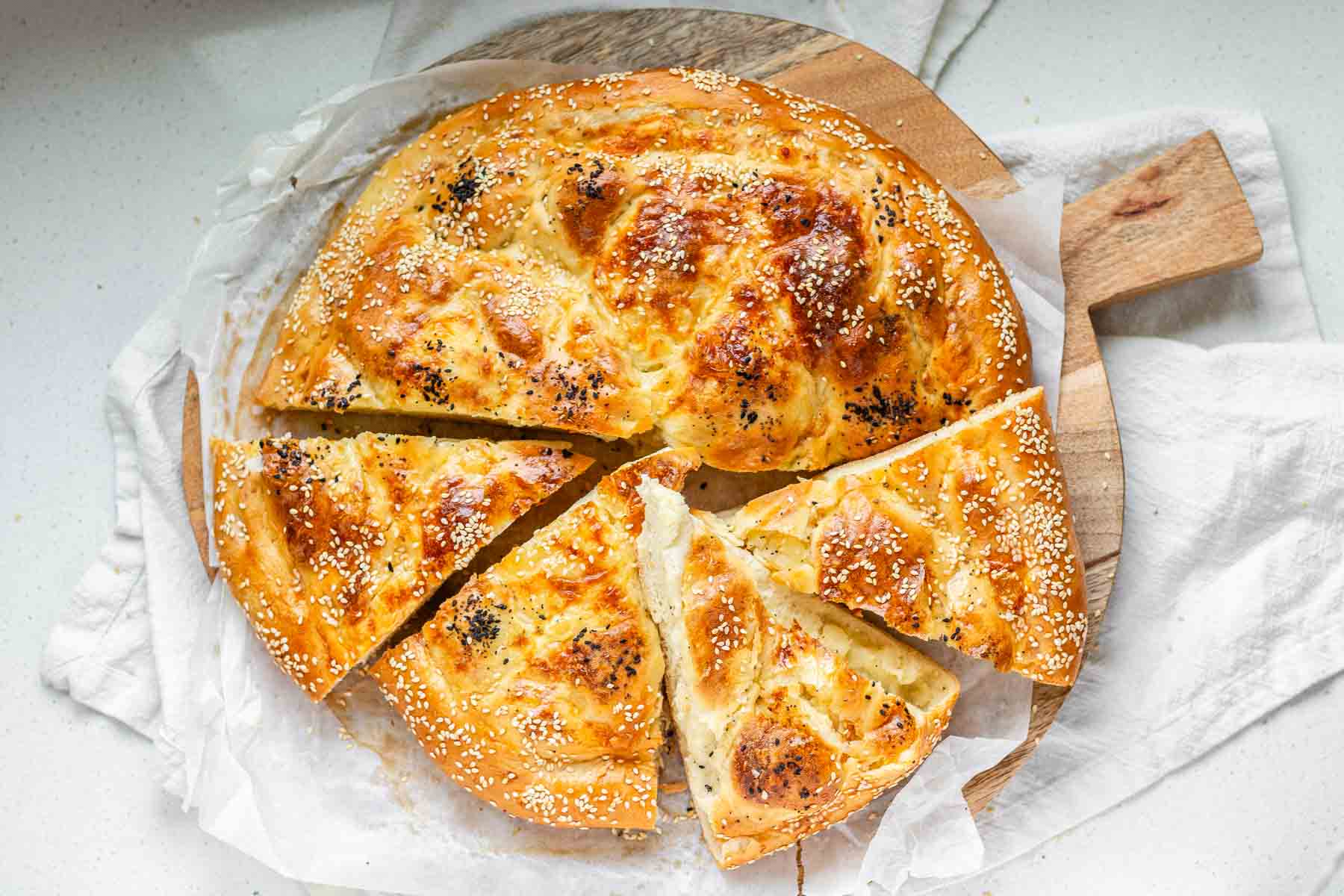 Sliced round flatbread topped with seeds.