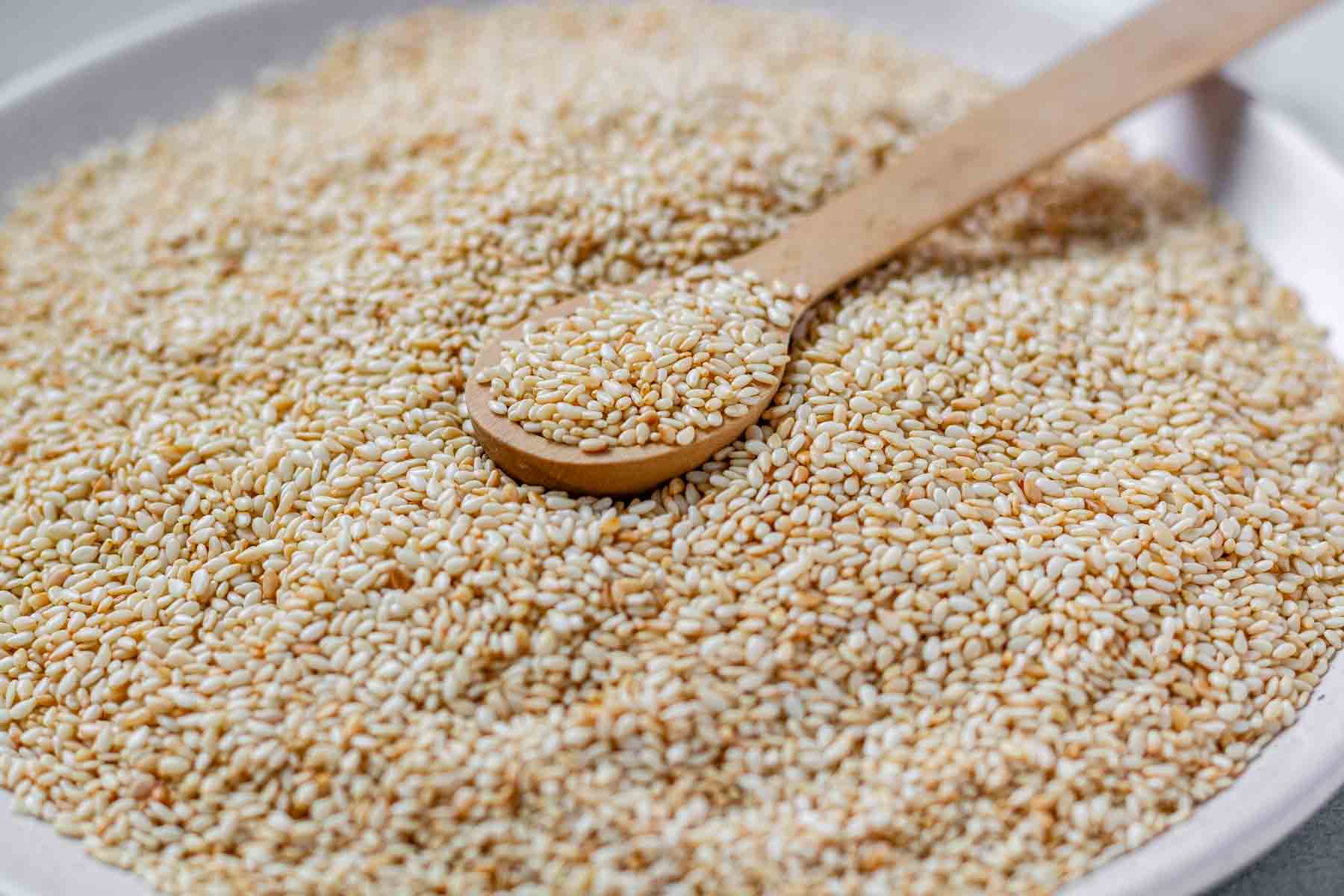 Golden toasted sesame seeds cooling on a plate.