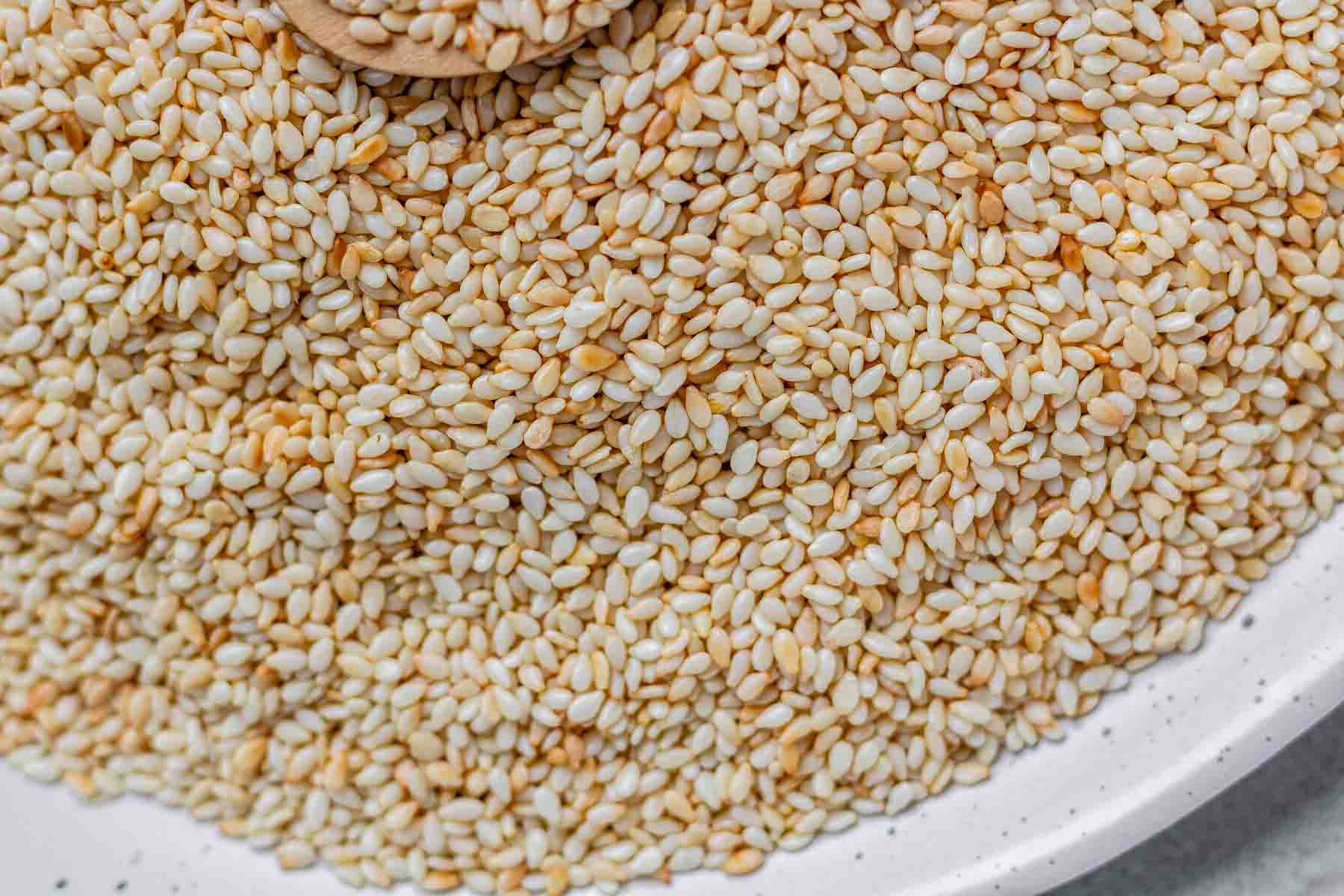 Golden toasted sesame seeds cooling on a plate.